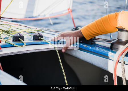 Des Menschen Hand mit Boot Seil. Yachtsman Mauren seinen Motor Boot am Steg. Nahaufnahme, Hände und Bug des Bootes. Stockfoto