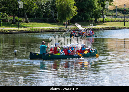 Grundschüler genießen einen freien Ausübung Aktivität Lektion, wie sie Spaß haben, Kanufahren auf trenance Garten See zum Bootfahren in Newquay in Cornwall. Stockfoto