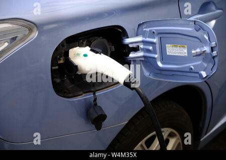 In der Nähe von EV-Elektroauto Ladestecker zu einem blauen Auto verbunden Stockfoto