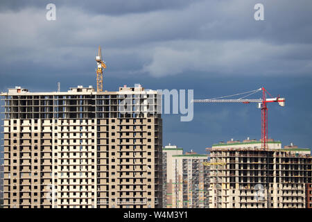 Baukräne und hohe Wohn- Gebäude im Bau auf dem Hintergrund der Sturm Himmel mit Wolken Stockfoto