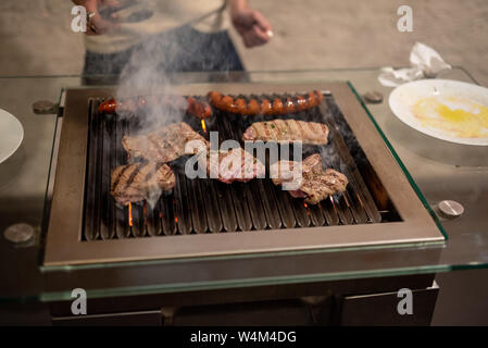 Verschiedene Arten von Fleisch, Rindfleisch Steaks und Würstchen, gekocht auf dem Grill innen Stockfoto