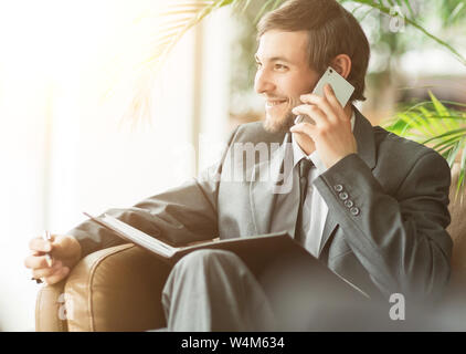 Zuversichtlich Geschäftsmann im Büro, am Telefon zu sprechen, schauen aus dem Fenster und Lächeln Stockfoto