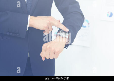 Auf der linken Seite des Fotos close-up der Geschäftsmann mit Finger zeigen auf die Uhr in der Hand. Auf der rechten Seite des Fotos auf dem Hintergrund der Stockfoto