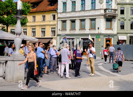 Ljubljana, Slowenien, 18. Juni 2019. Tour Guide mit einer Flagge der Führung einer Gruppe von asiatischen Touristen durch die Altstadt von Ljubljana Stockfoto