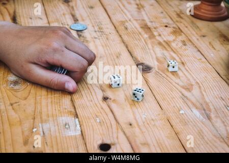 Spielen gleichzeitig ein Spiel spielen mit Würfeln auf einem Holztisch Stockfoto