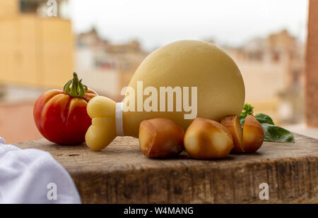 Käse, italienischen Provolone Caciocavallo gealtert und geräuchertem Käse in teardrop Form mit gelben houises der alten italienischen Stadt auf Hintergrund Stockfoto