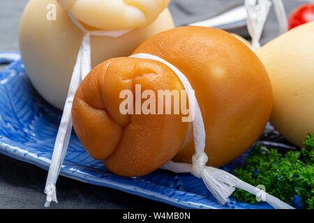 Käse, italienischen Provolone Caciocavallo gealtert und geräuchertem Käse in teardrop Form auf blauem Teller Nahaufnahme Stockfoto