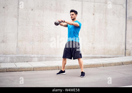 Gesundheit und Fitness Concept. Mann tun kettlebell swing Übungen während der städtischen Training Session Stockfoto