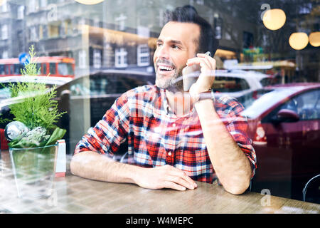 Mann sitzt im Cafe in der Weihnachtszeit und am Telefon sprechen Stockfoto