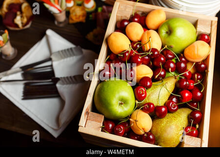 Bild von oben, der Holzkiste mit Kirschen, Äpfel, Aprikosen, Birnen auf Tisch Stockfoto