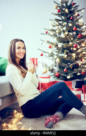 Lächelnde Frau Tee trinken und entspannen während Weihnachten Stockfoto
