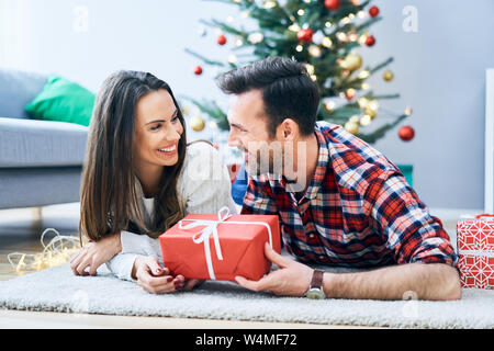 Nettes Paar entspannen im Wohnzimmer und den Austausch von Weihnachtsgeschenk Stockfoto