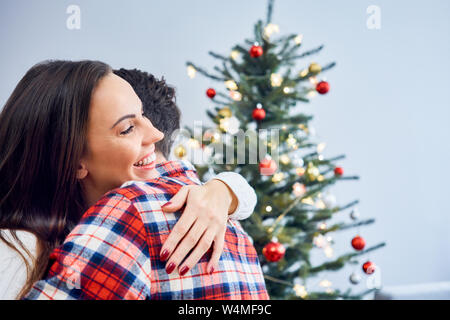 Portrait von glücklichen Paare, die während der Weihnachtsfeier mit Dekorationen im Hintergrund Stockfoto