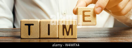Ein Mann legt Holzblöcke mit dem Wort Zeit. Konzept der Zeit Verwaltung und ordnungsgemäße Verteilung. Planung Wirtschaft und Arbeit. Business Jugend. Analyse Stockfoto