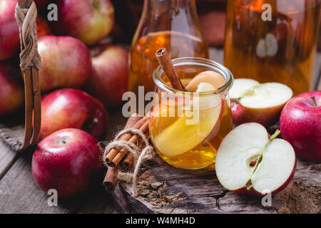 Glas Apfelsaft mit in Scheiben geschnittenen Äpfel und Zimtstangen auf einem rustikalen Oberfläche Stockfoto