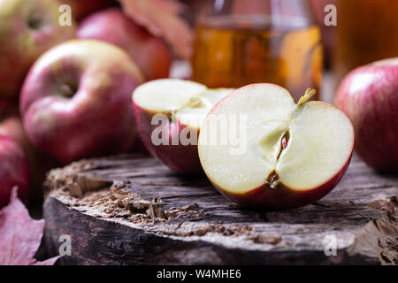 Nahaufnahme von einem Apple geschnitten in der Hälfte auf Holzmöbeln im Landhausstil Oberfläche mit Äpfeln und Saft im Hintergrund Stockfoto