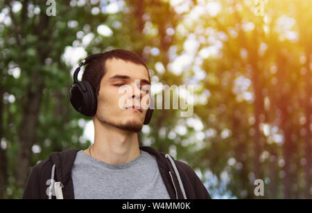 Schöner Mann in Kopfhörer Musik hören Outdoor.