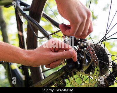 Männliche Radfahrer Reparaturen Bremse hinten mit dem Mountainbike im Wald Stockfoto