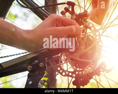 Männliche Radfahrer Reparaturen Bremse hinten mit dem Mountainbike im Wald Stockfoto