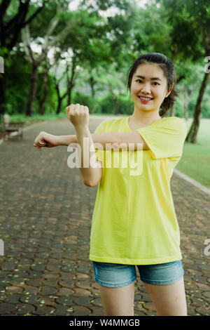 Hübsche junge Asiatin üben Übung im Park am Morgen. Frische und gesunde Lebensweise für Menschen. Stockfoto