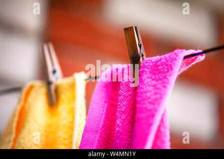 Zwei Handtücher mit Wäscheklammern hängen auf der Wäscheleine im Freien. Stockfoto