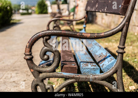 Das Metall rostet Die auf der Holzbank im Park Griff an einem sonnigen Sommertag und verschwommenen Hintergrund. Close Up, selektiver Fokus Stockfoto