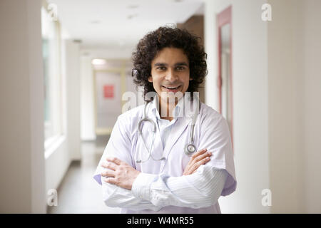 Männlichen Arzt lächelnd mit seinem verschränkten Armen Stockfoto