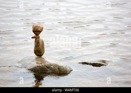 Stein balancing im Loch ein Eilein im Rothiemurchus Wald, Cairngorm, Schottland, Großbritannien. Stockfoto