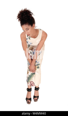 Eine wunderschöne junge multi-rassischen Frau in einer langen Sommer Kleid und Highheels, Biegen, Vorwärts, schauen in die Kamera mit ihrem schwarzen lockigen Haar in Stockfoto