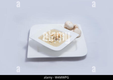 Held Schuß eines Pilzsuppe mit Brotkrumen, Oregano auf einer minimalen weißen Hintergrund mit einem Winkel von 45° Stockfoto