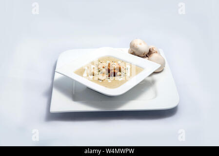 Held Schuß eines Pilzsuppe mit Brotkrumen, Oregano auf einer minimalen weißen Hintergrund mit einem Winkel von 45° Stockfoto