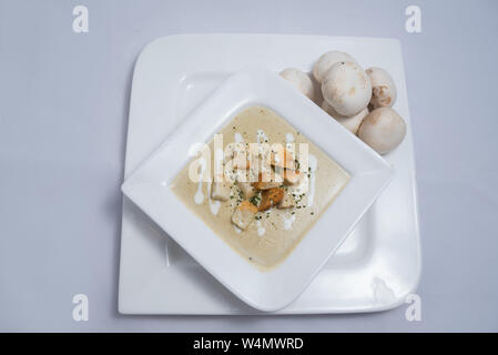 Held Schuß eines Pilzsuppe mit Brotkrumen, Oregano auf einer minimalen weißen Hintergrund mit einem Winkel von 45° Stockfoto