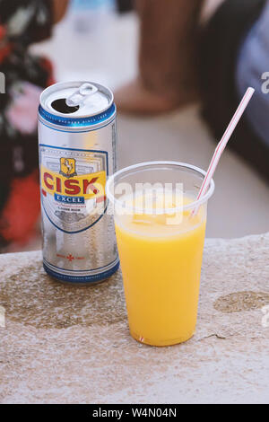 Valletta, Malta - Juni 28, 2019: Kann der maltesischen lokale Cisk Bier Lagerbier und Orangensaft in Schale aus Kunststoff mit Stroh auf der Straße Stockfoto