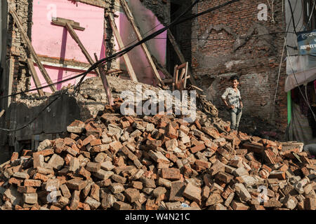 Mann stand auf einem Haufen Steine aus einem eingestürzten Haus nach einem Erdbeben in Kathmandu, Nepal Stockfoto