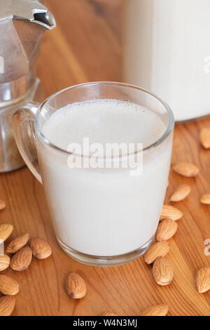 Glas Mandelmilch und Kaffeemaschine auf Holz Tabelle, Ansicht von oben. Vegan Mandel trinken und Espresso Moka Teekocher - auf Basis pflanzlicher Ersatz für Kaffee Stockfoto