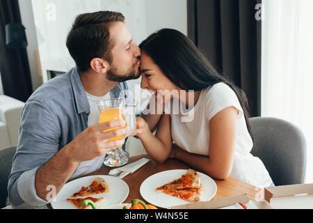 Glückliches Paar küssen und ein Abendessen mit Pizza zu Hause. Es ist eine gute Zeit verbringen Home Stockfoto