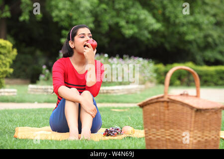 Frau, die einen Apfel isst, bei einem Picknick Stockfoto