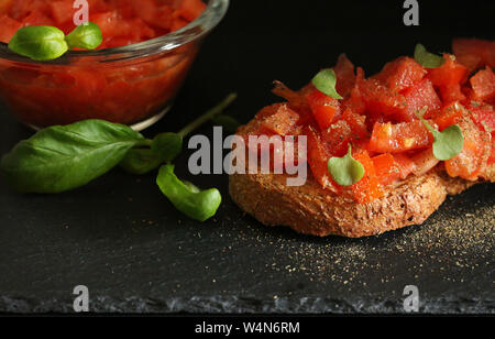 Bruschetta mit Tomaten und Basilikum auf dunklem Hintergrund Stockfoto
