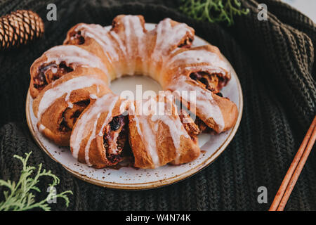 Schwedische Kaffee ring Christmas Cake mit Zimt, Pekannüsse und Rosinen an einem warmen gestrickte Pullover. Das Konzept der gemütlichen Winterurlaub und hausgemachte Backwaren. Stockfoto