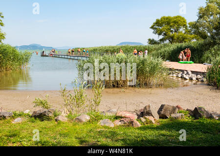 Naturstrand mit Badenden zu Fuß auf Pier am Plattensee, Ungarn Stockfoto