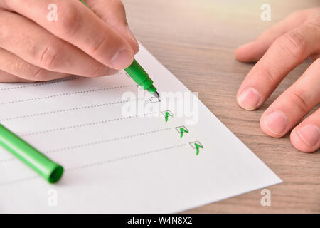 Konzept der Hand mit grünen Marker Pen das Ausfüllen eines Fragebogens auf ein Blatt Papier auf einem Holztisch. Horizontale Komposition. Erhöhte anzeigen. Stockfoto