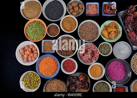 Auf einem schwarzen Hintergrund, Arten und Hülsenfrüchte., Hibiscus, gelbe Linsen, grüne Linsen, rosa Reis, Sternanis, Kichererbsen, Sesam, oat Seeds Stockfoto