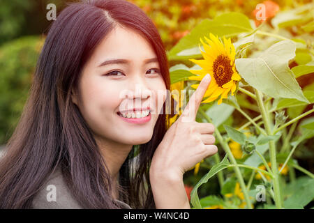 Glücklich lächelnde asiatische Jugendliche Hand im Sunflower zeigen Stockfoto