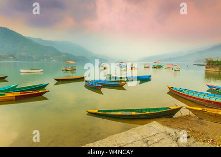 Bunte Boote in Phewa See geparkt für Touristen und Hintergrund auf Sonnenuntergang Blick vom See in Pokhara Nepal wartet. Stockfoto