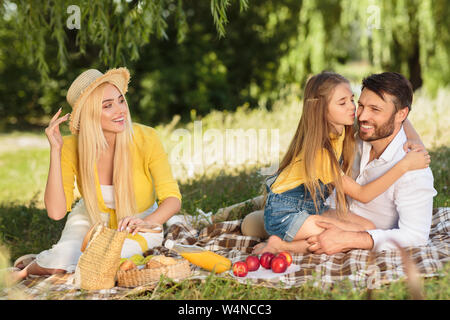 Familie Picknick. Tochter Vater auf die Wange küssen Stockfoto