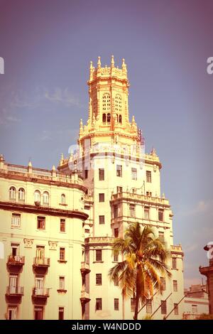 Havanna, Kuba - Stadt Architektur. Eklektisches Gebäude und Palmen. Kreuz verarbeitet Farbton - retro style gefilterten Bild. Stockfoto
