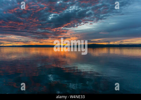 Die Wolken hängen am Himmel, wie die Sonne hinter den Olympic Mountains im Armaturenbrett, Washington. Stockfoto