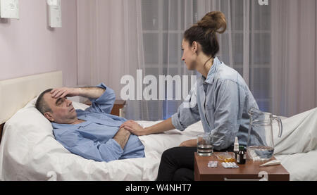 Tochter besuchen ältere Vater im Krankenhaus und medizinische Arbeiter zu sprechen Stockfoto