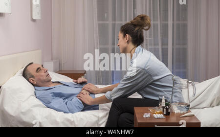 Tochter besuchen ältere Vater im Krankenhaus und medizinische Arbeiter zu sprechen Stockfoto