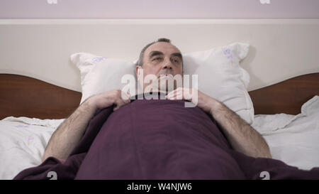 Ein älterer Mann liegt in seinem Bett einschlafen, Erwachen aus einem Traum, Furcht, Angst Stockfoto